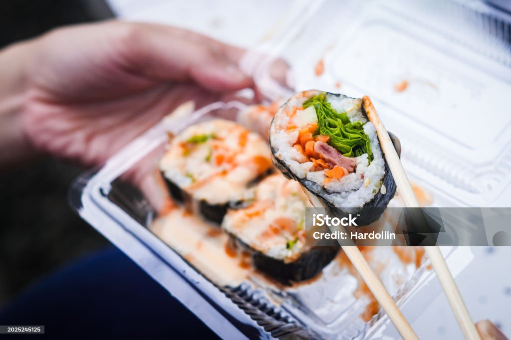 Holding sushi with chopstick from a takeout container